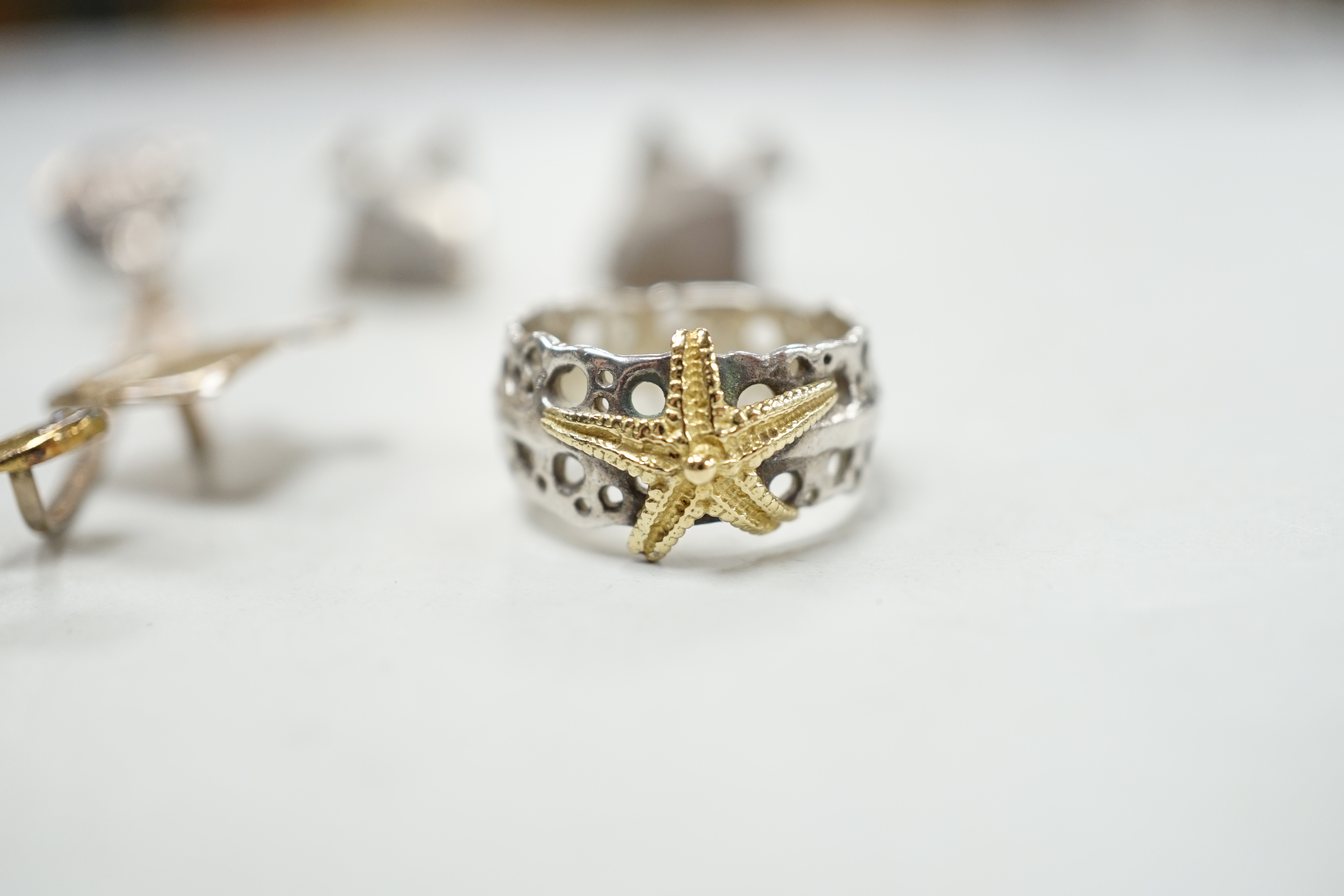 A modern Alan Vallis parcel gilt silver ring, with starfish motif, size O and two pairs of Alan Vallis silver earrings, both modelled with fish, longest overall 74mm.